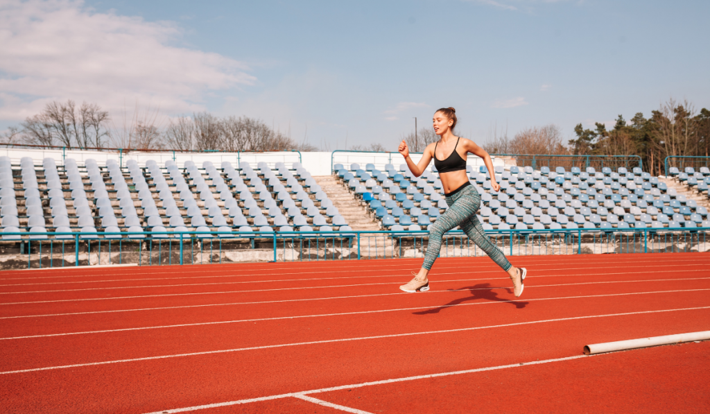 Beautiful sportive caucasian woman running on the running track. Morning training at the stadium