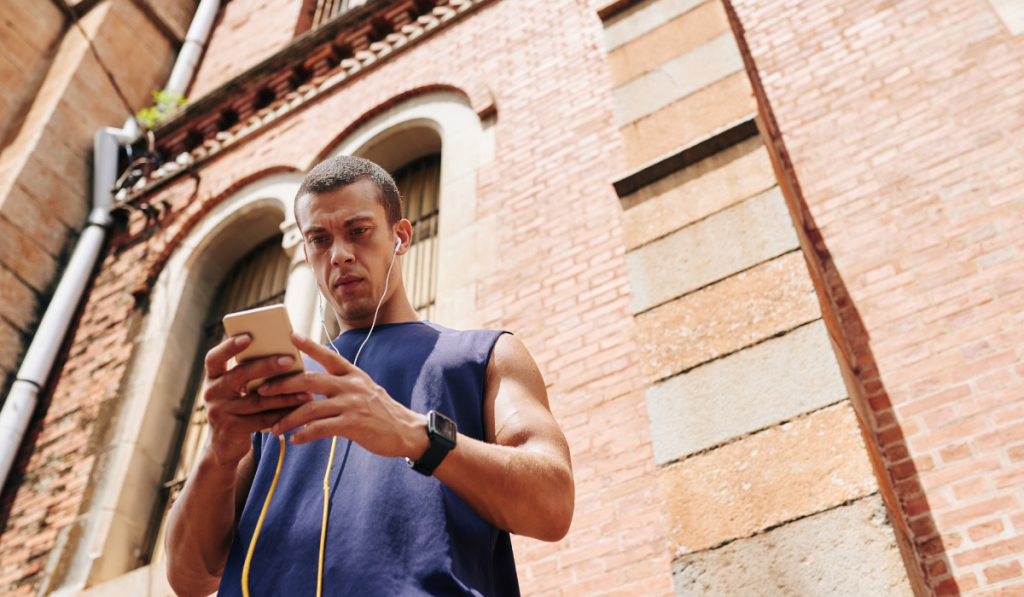 Sportsman choosing music track for jogging on his smartphone