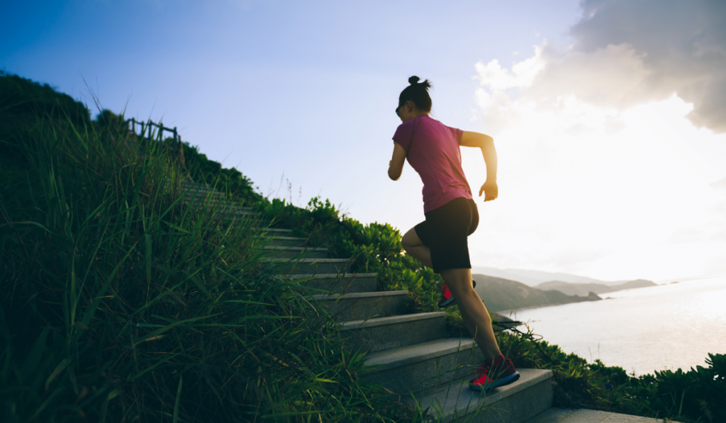 Determined woman running up on seaside mountain stairs