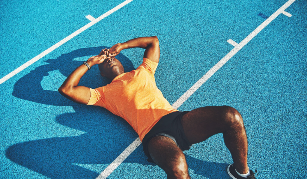 Exhausted young athletic lying on a running track after training