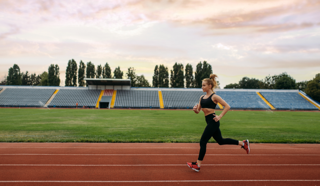 Female runner jogging, training on stadium using the heel strike running