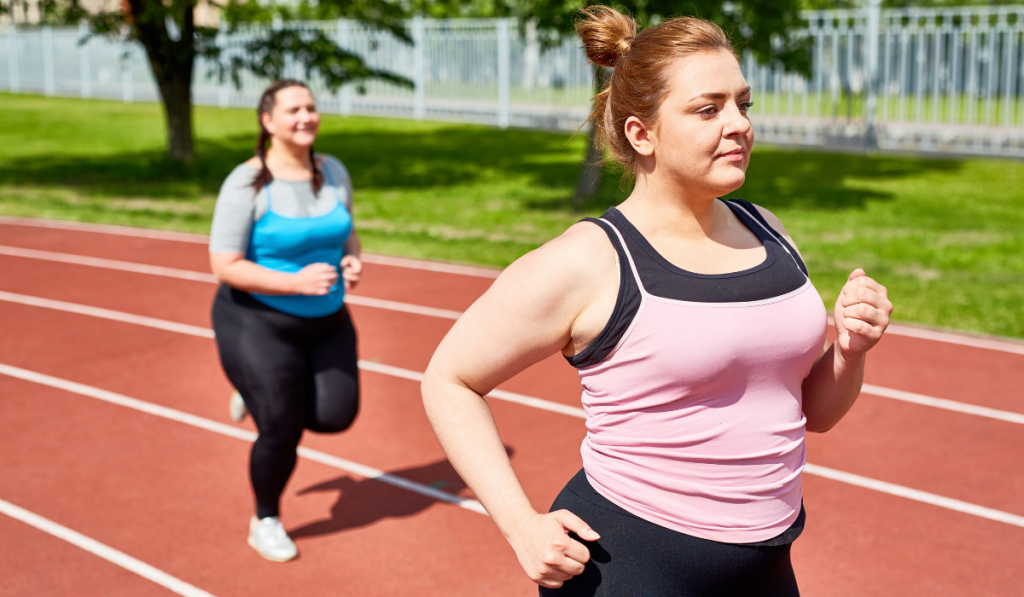 Active and determined over-sized women jogging on stadium in the morning

