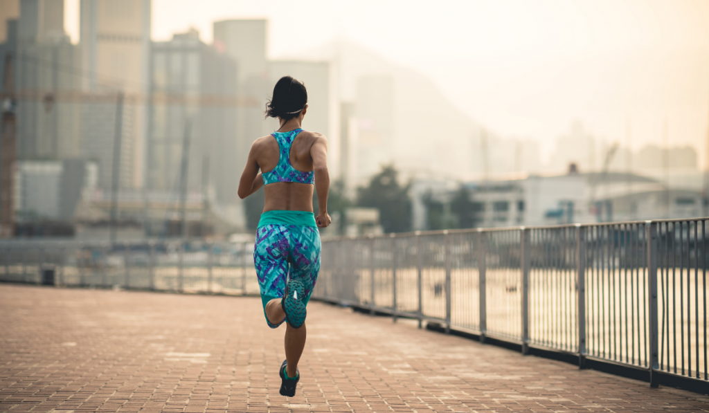 Healthy lifestyle woman runner running on foggy city at sunset

