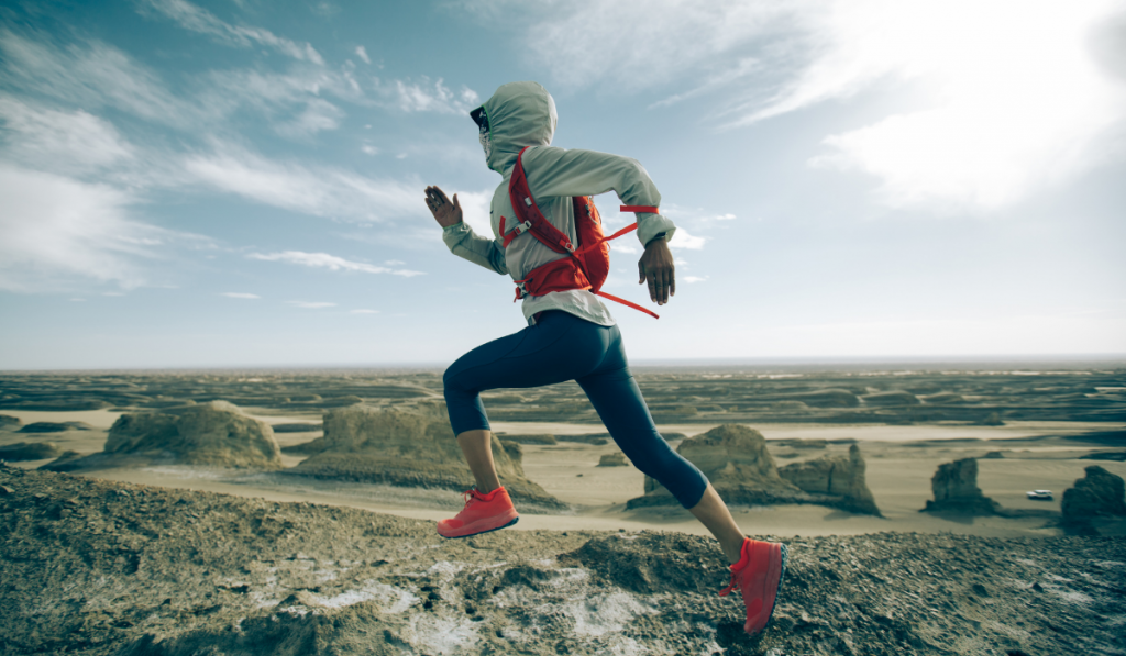 Woman trail runner cross country running on sand desert hill top