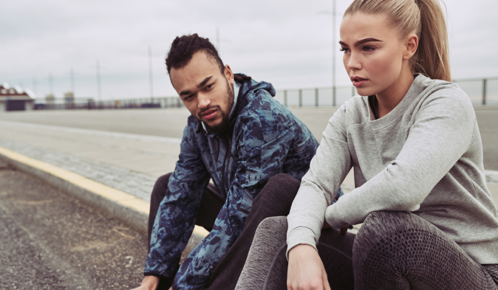 Tired couple resting on a road during an outdoor run