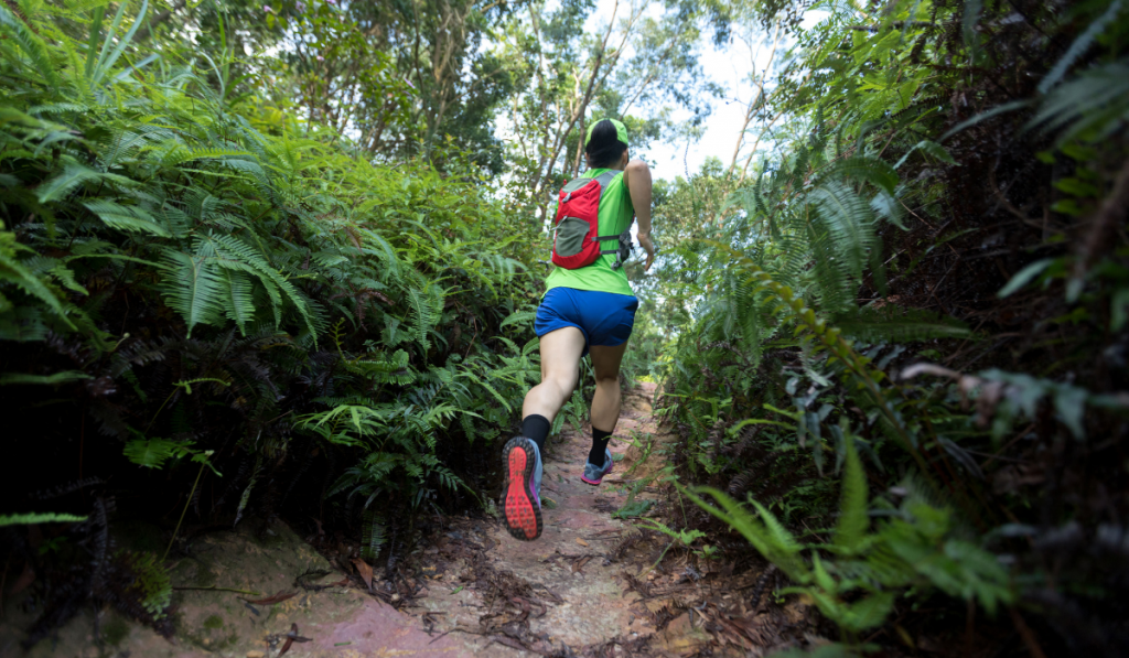 Woman ultra marathon runner running on tropical forest trail