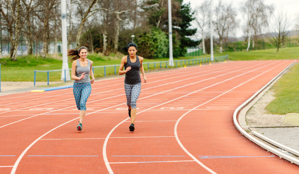 Two young women running on running track