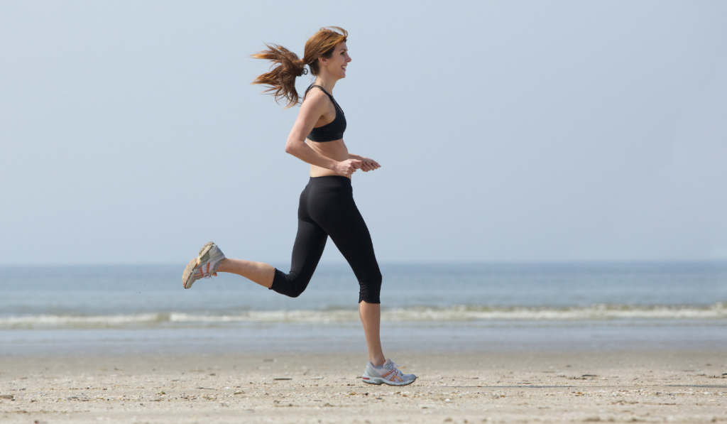 Woman runner enjoying exercise at the beach on midfoot strike running