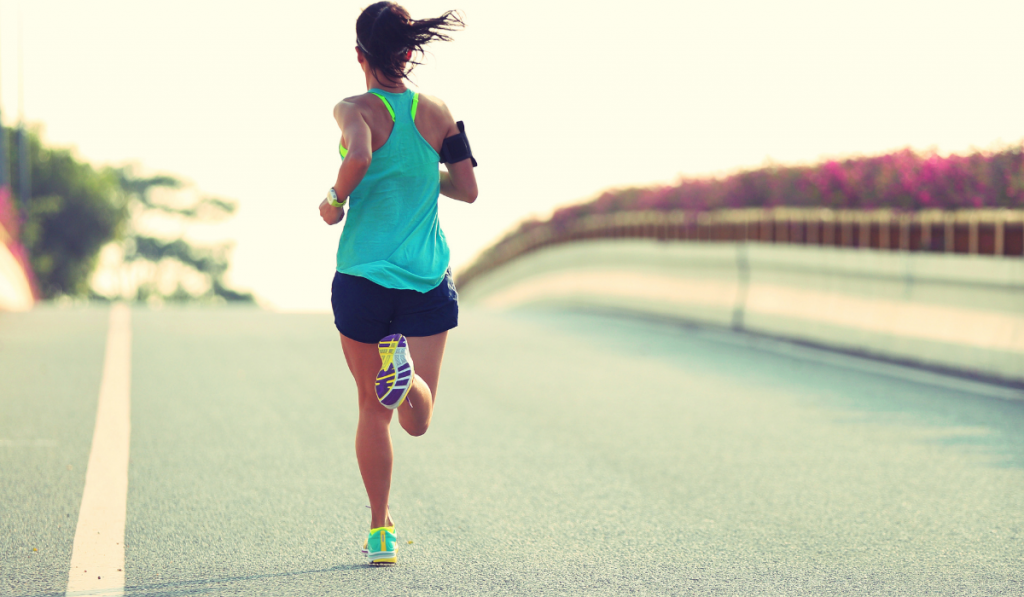 Young woman runner running on city road
