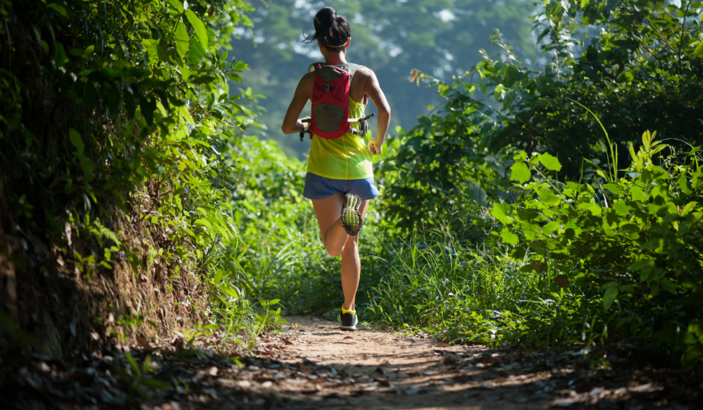 Young woman trail runner running on tropical forest trail