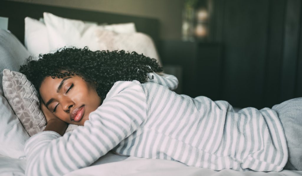 closeup pretty black woman curly hair sleeping in bed 