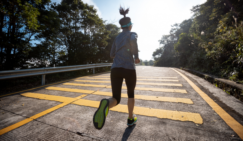 Woman runner running on mountain top on sunny day