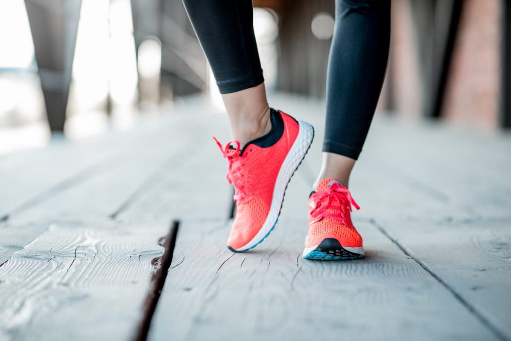 female showing off her orange running shoes 