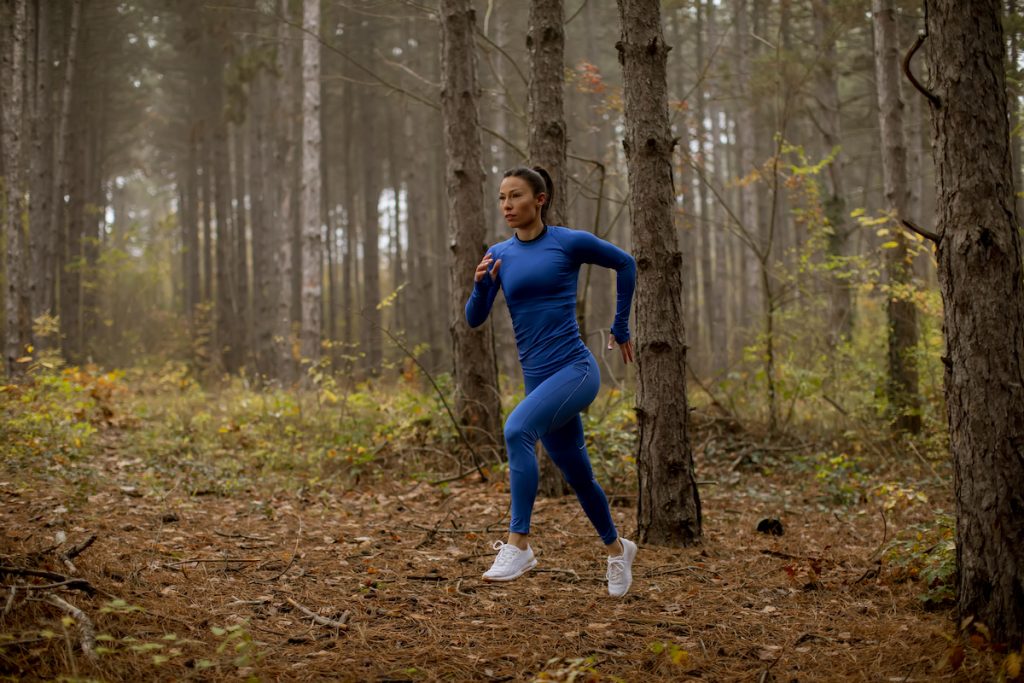 woman running on a forest trail in autumn