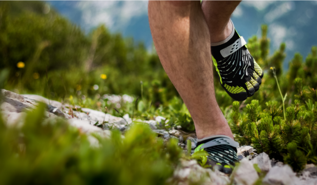 man running in a rock path wearing barefoot shoes